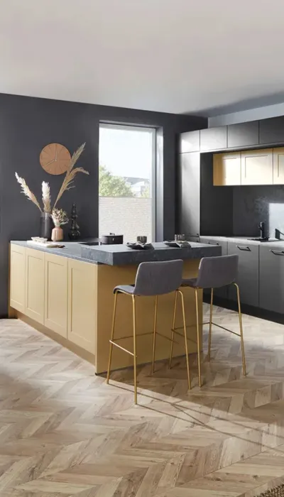 Stilvolle Küche mit dunkler Küchenzeile und auffälliger senffarbener Kochinsel, kombiniert mit edlen Barhockern und dekorativen Trockenblumen, ideal für moderne Designliebhaber.